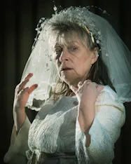 Gunilla Röör som Rut. Gunilla bär en vit klänning och brudslöja på huvudet. 