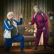 Per Sandberg och Gunilla Röör, iklädda träningsoveraller, i rollerna som Rut och Ragnar. 