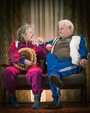 Per Sandberg och Gunilla Röör, iklädda träningsoveraller, i rollerna som Rut och Ragnar. 