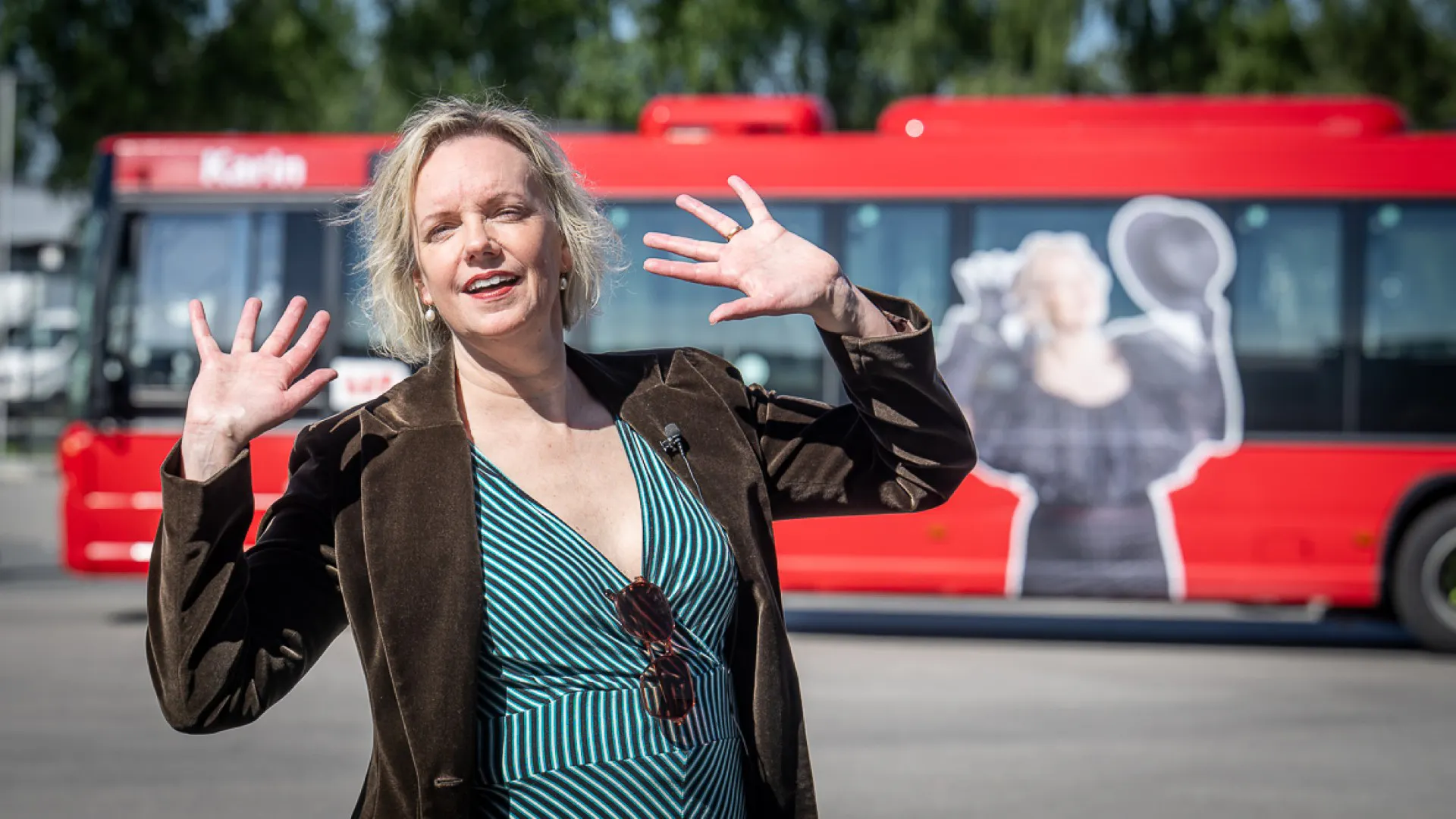 Karin Paulin framför en röd LLT-buss med hennes bild på. 