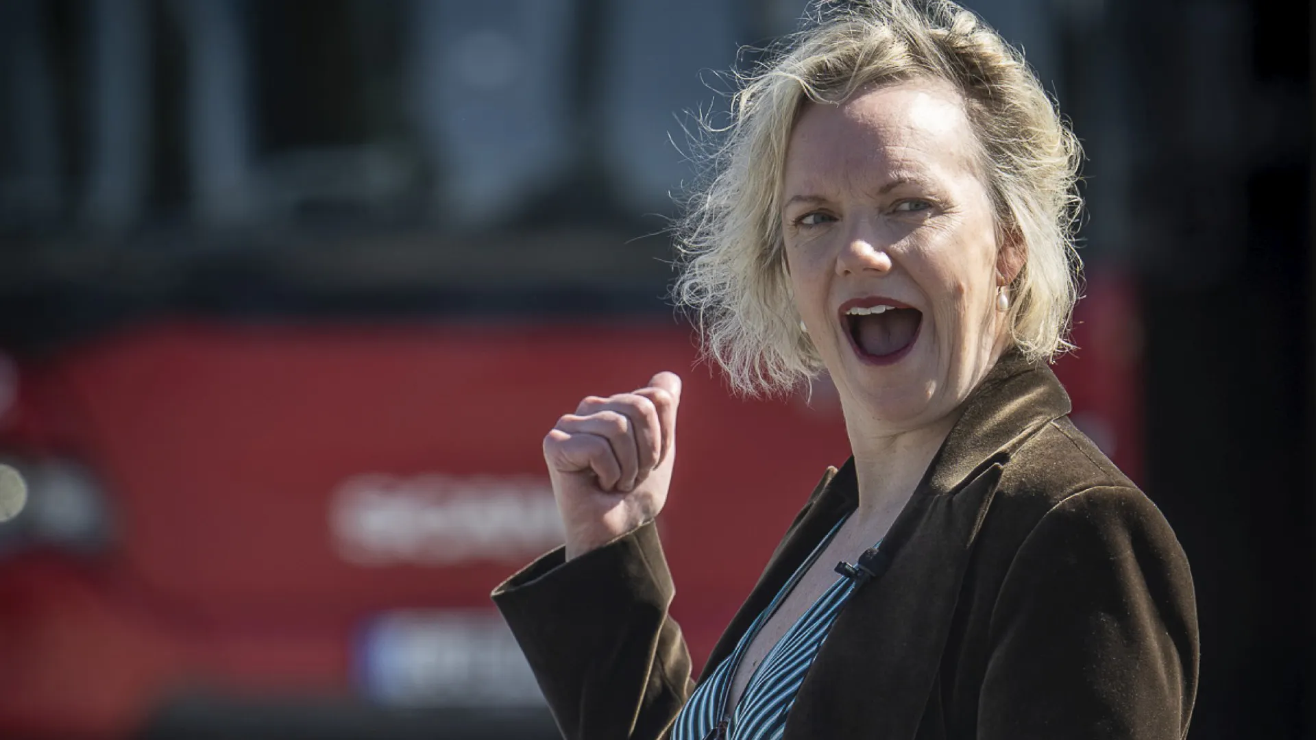 Karin Paulin framför en röd LLT-buss med hennes bild på. 